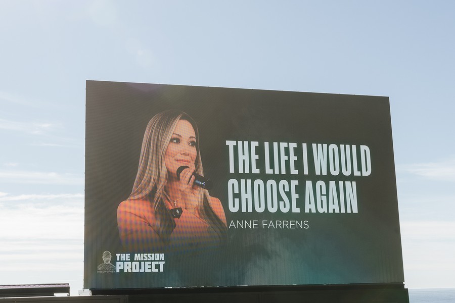 Anne Farrens speaking on stage, shown on the event jumbotron